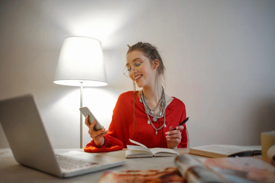 A person sitting at a clean desk, smiling as they read an email on a laptop.